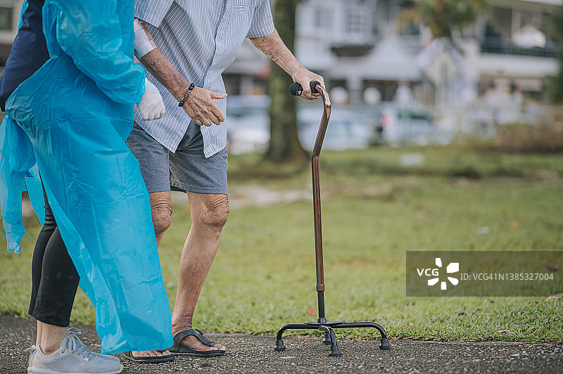 亚裔中国女性理疗师帮助老人拄着拐杖在公园散步图片素材
