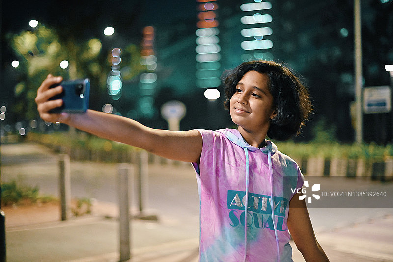晚上站在城市街道上自拍的少女图片素材