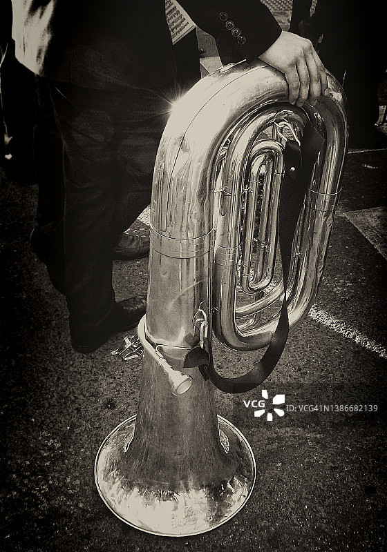 在游行队伍中的一站。西班牙格拉纳达的大街上，大号演奏者在他的乐器上休息图片素材