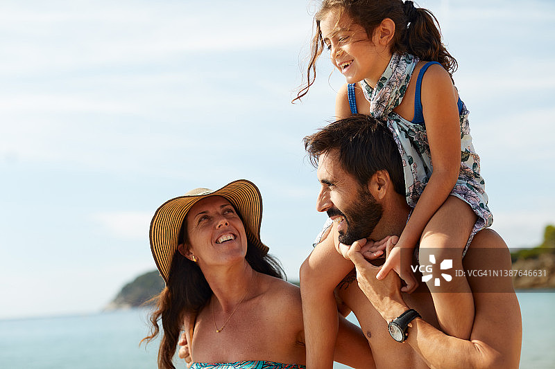 一家人带着一个女儿在地中海海滩度假。图片素材