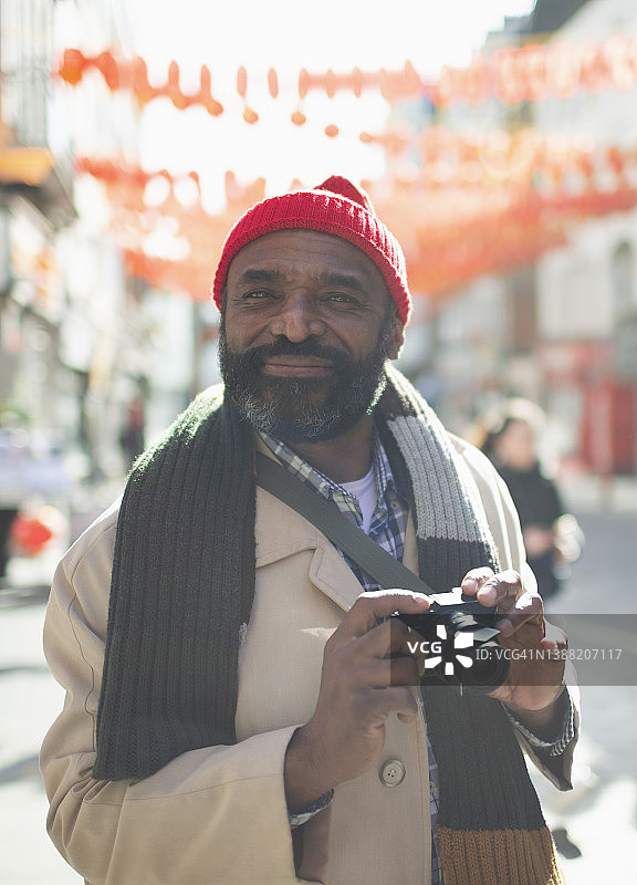 肖像英俊的男性游客与数码相机在阳光城市图片素材