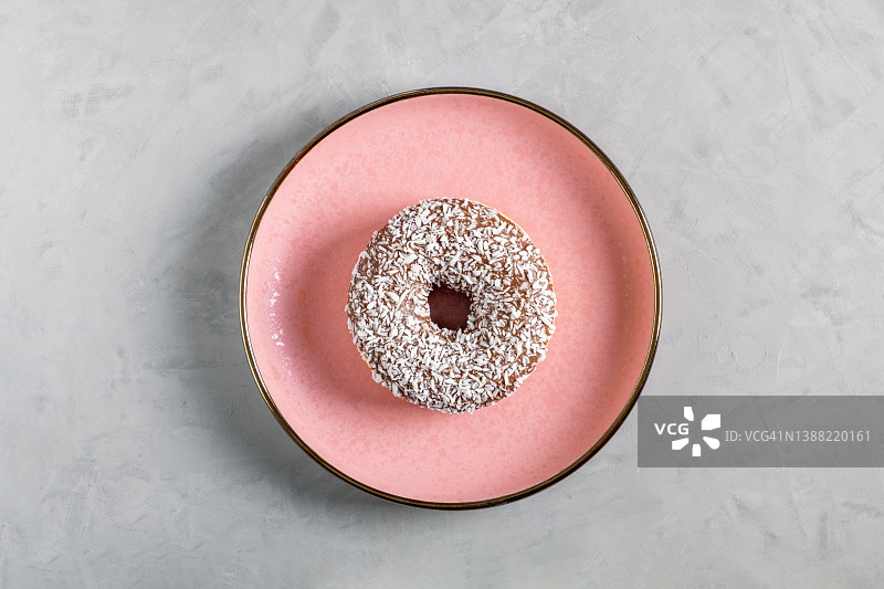 一个粉红色的陶瓷盘子里放着椰子馅的甜甜圈图片素材