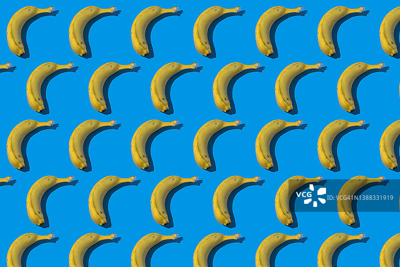 香蕉图案与硬阴影，在蓝色背景。健康饮食的概念，水果，钾和加那利群岛。图片素材