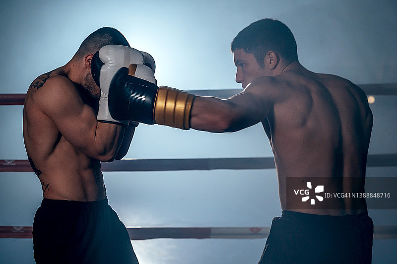 两个肌肉发达的年轻男性拳击手在拳击台上格斗。高质量的摄影。图片素材