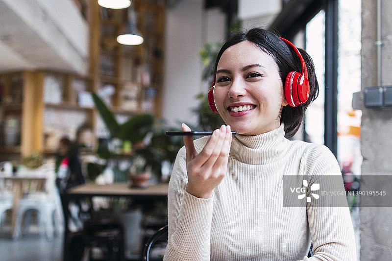 咖啡馆里一个快乐的女人戴着无线耳机用扬声器打电话图片素材