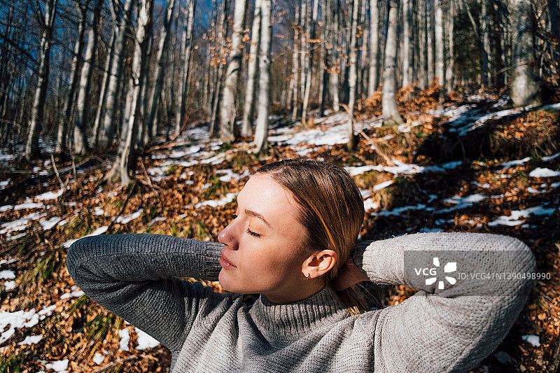 年轻女子在森林里享受冬日的阳光图片素材