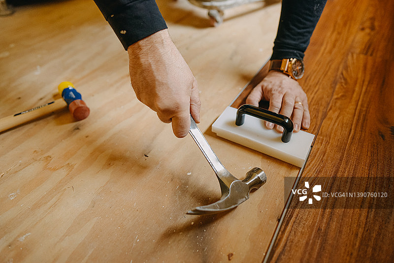 安装木地板时，男性手握锤子图片素材
