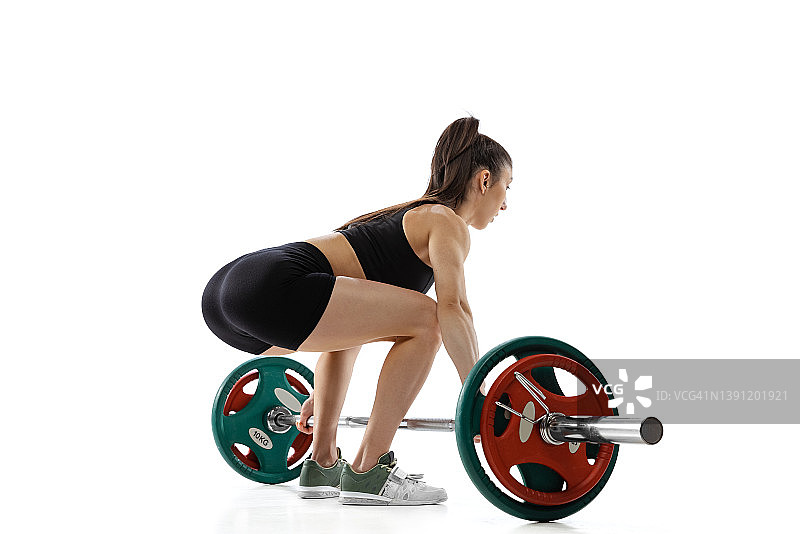 一位年轻强壮的女举重运动员在白色背景下练习杠铃。运动，举重概念图片素材