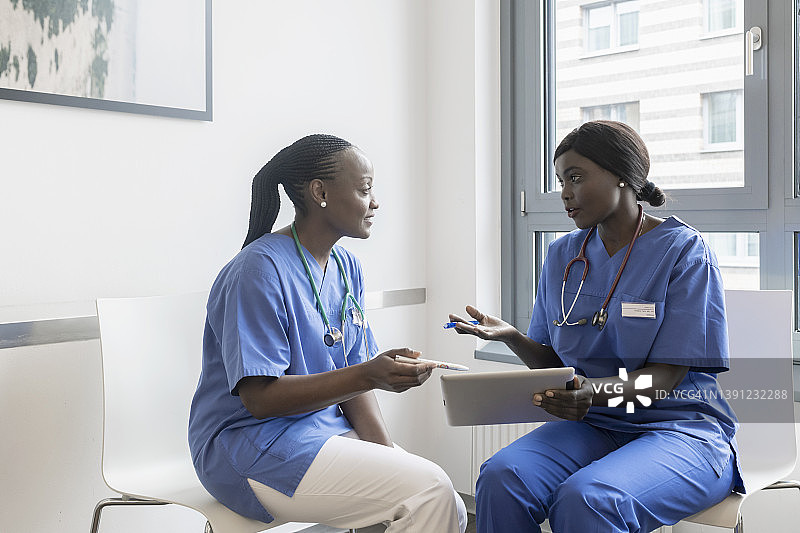 两名女医生在候诊室用数码平板电脑讨论体检结果图片素材