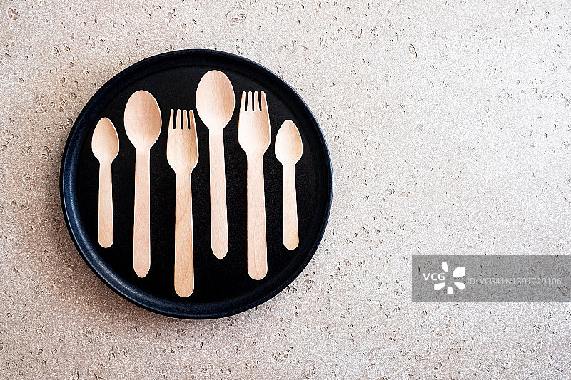 一组木制汤匙，叉子和茶匙在一个黑色的盘子或托盘上的混凝土背景，俯视图。零浪费的概念。副本的空间。图片素材