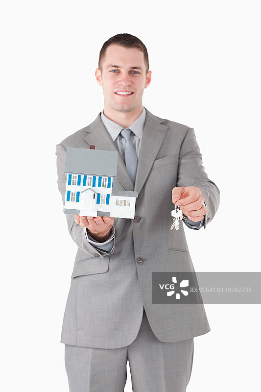 一个商人拿着迷你房子和钥匙的肖像图片素材