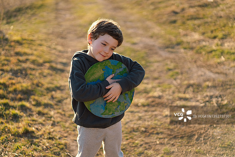 小男孩手里拿着星球，背景是绿色的春天图片素材