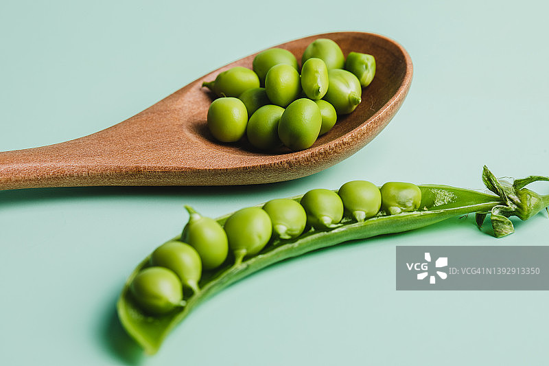 绿豌豆放在木勺上，绿色背景衬托图片素材