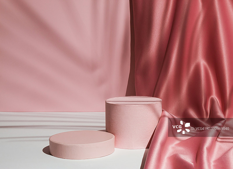 柔和的粉红色组成与缎面窗帘和棕榈叶阴影。适合产品展示和商业理念。现代美学。图片素材