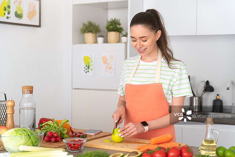 年轻的素食女性在厨房做健康的饭菜，切苹果图片素材