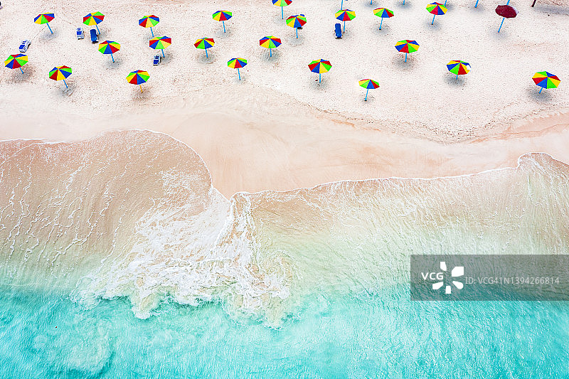 安提瓜和巴布达，热带沙滩上被海浪冲刷的阳伞图片素材