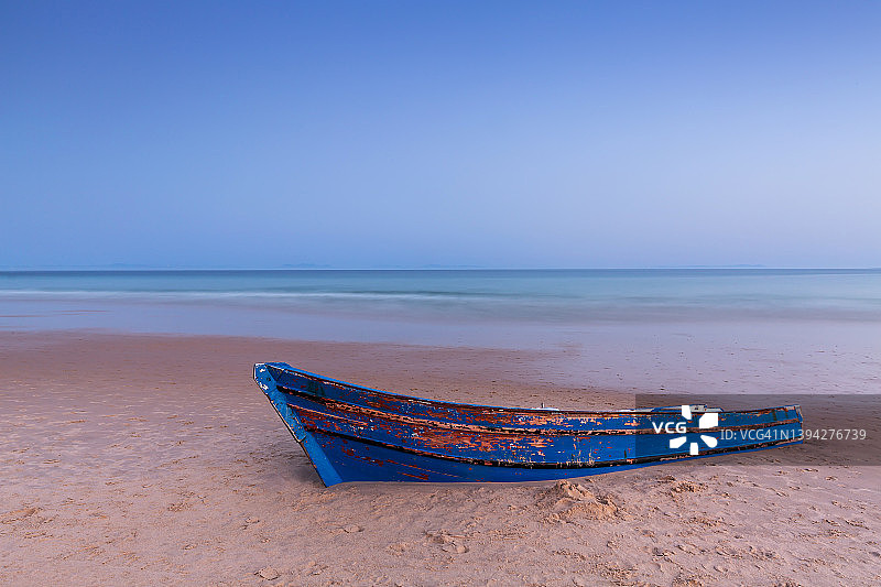 日落时沙滩上被遗忘的划艇图片素材
