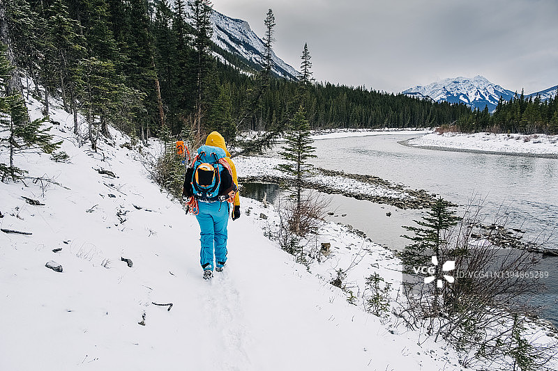 在班夫国家公园，一名女子在雪地里沿着河岸走着图片素材