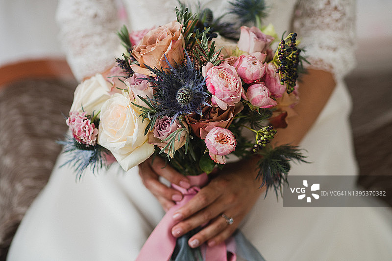 特写的白人新娘持有一个美丽的婚礼花束色彩鲜艳的鲜花在她的手。图片素材