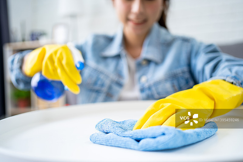 年轻漂亮的亚洲女人用超细纤维抹布打扫房子。管家的概念。图片素材