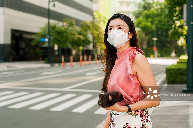 一名穿着时髦休闲服、戴着防护口罩的东南亚女性正步行去市区上班图片素材