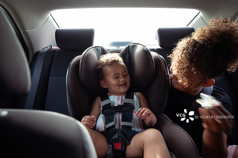可爱的小孩子姐妹们一起在车里玩耍，系好安全带。图片素材