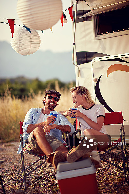 一对夫妇在露营房车前闲聊和大笑。Roadtrip暑假。乐趣，相聚，旅行，自然的概念。图片素材