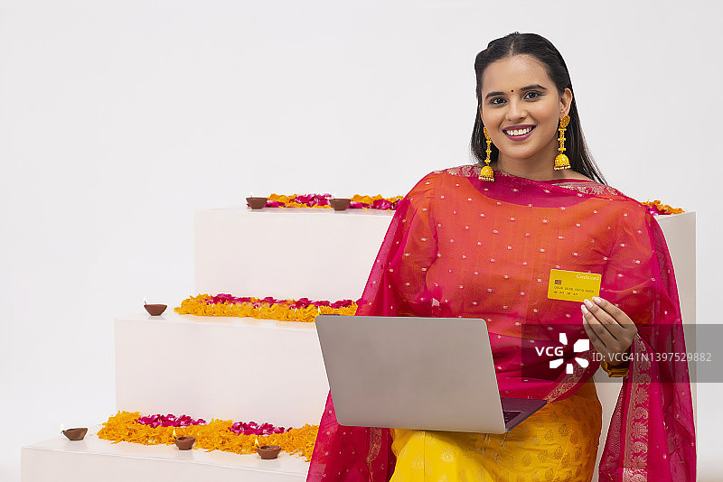 印度女士在节日期间通过笔记本电脑使用借记卡在线购物图片素材