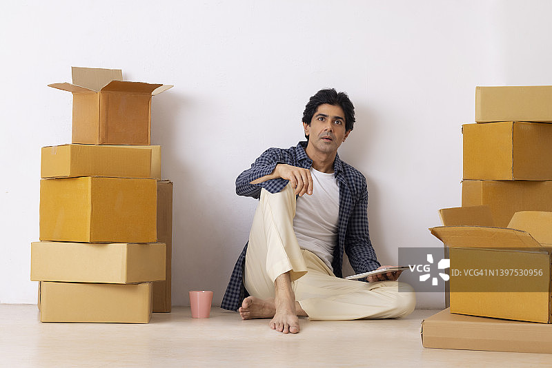 印度男子在搬新家时用平板电脑思考图片素材