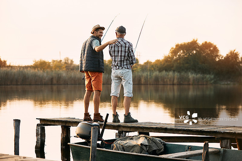 快乐的男人和他年长的父亲享受淡水钓鱼的背影。图片素材