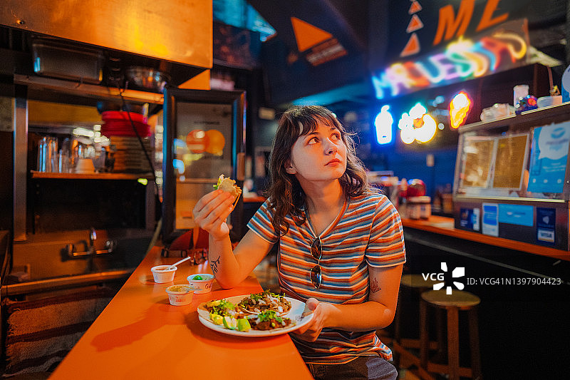 一个女人在酒吧里吃玉米卷图片素材