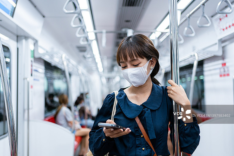 年轻的亚洲女性在上下班途中使用智能手机图片素材