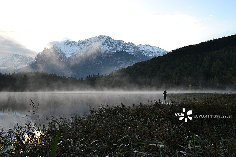 人站在山湖树木和雾在黎明巴伐利亚图片素材