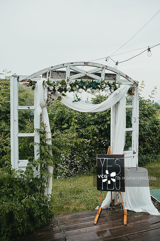 在户外婚礼。用玫瑰装饰的白色拱门。图片素材
