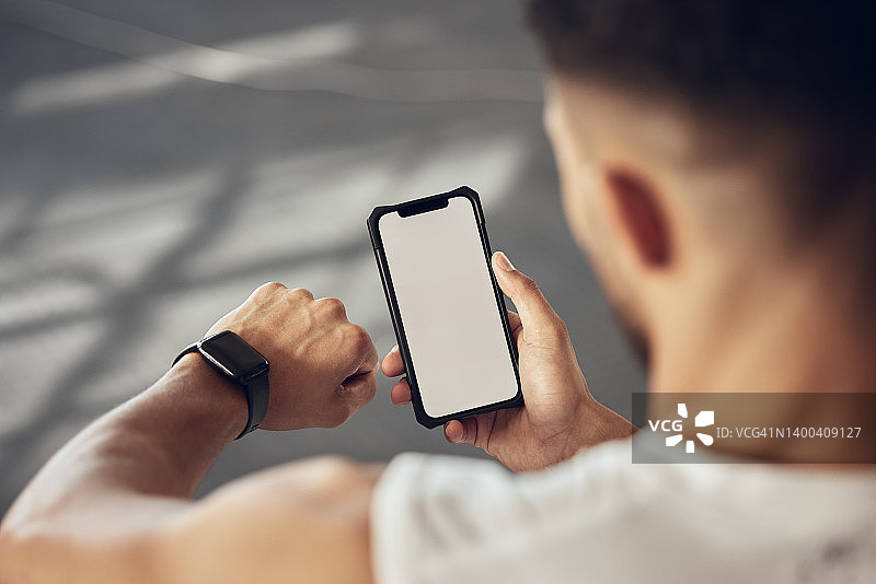 运动员用他们的智能手机追踪他们的进度。健美男子使用手表跟踪锻炼进度。运动员在健身房使用在线应用程序连接他们的手表和手机图片素材