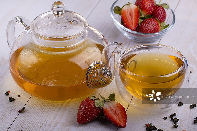绿茶乌龙茶用草莓在玻璃透明杯和玻璃茶壶，红糖，特写，选择性聚焦杯图片素材