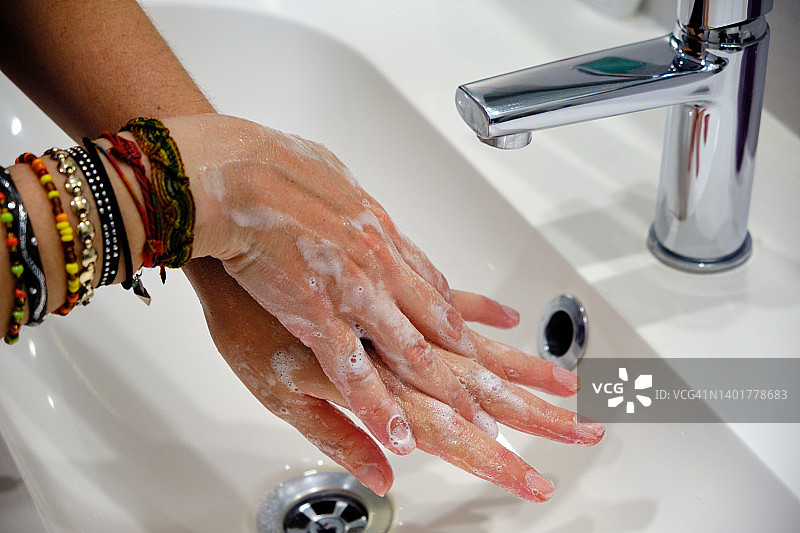 女人用肥皂，在水龙头下洗手。图片素材