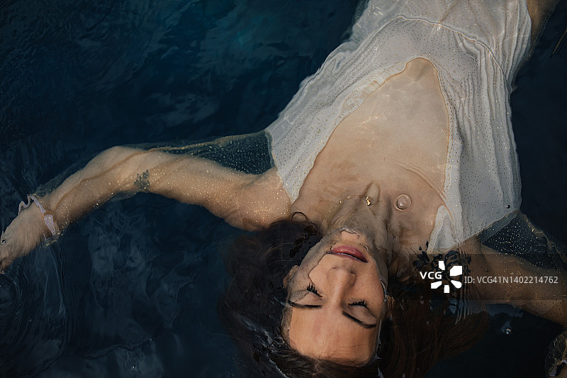 冥想的年轻女子在海水中漂浮，双臂伸展图片素材