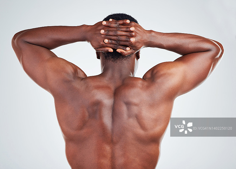 一个非裔美国健身模特的后视图，在白色背景下摆姿势。难以辨认的黑人男子展示他的肌肉形状，而孤立的白色copyspace图片素材