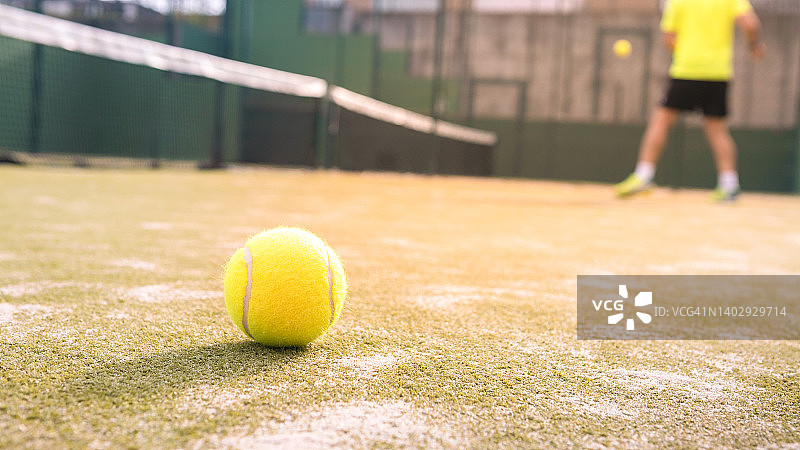 室外绿色场地球拍网后面的地板上有黄色的球。帕德尔网球图片素材