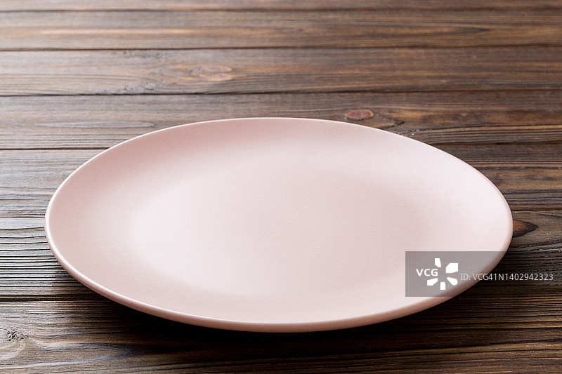 木制背景上的空粉色盘子的透视视图。为你的设计留出空间图片素材