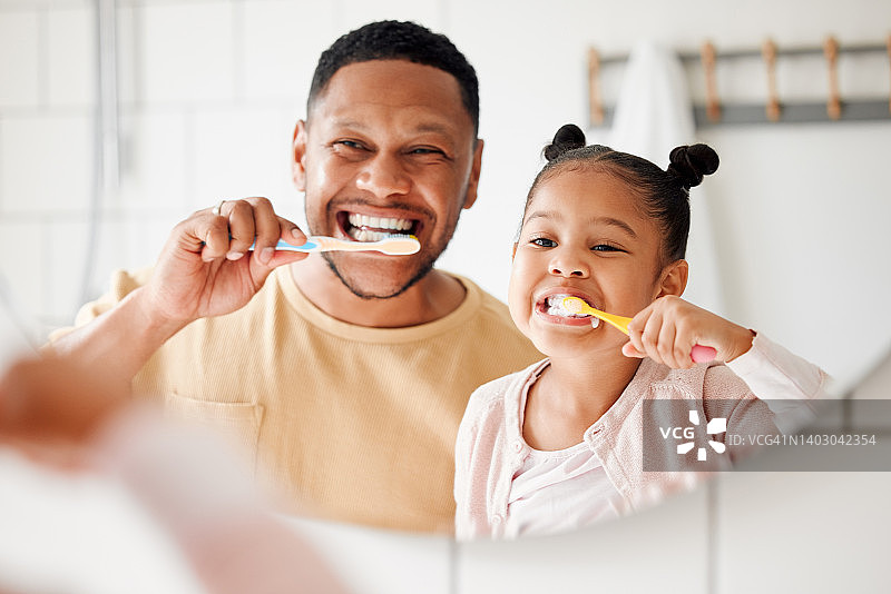 幸福的混血父女在家里的浴室里一起刷牙。单亲非裔美国父母教他的女儿保护牙齿图片素材