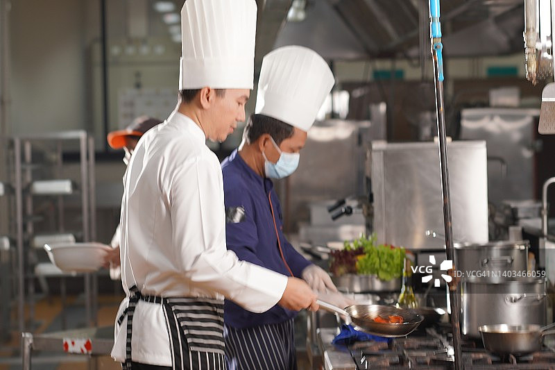 泰国，欢快的厨师在商业厨房准备食物。图片素材
