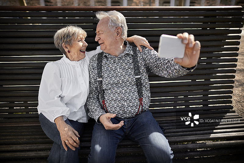 一对快乐的老年夫妇在长椅上自拍图片素材
