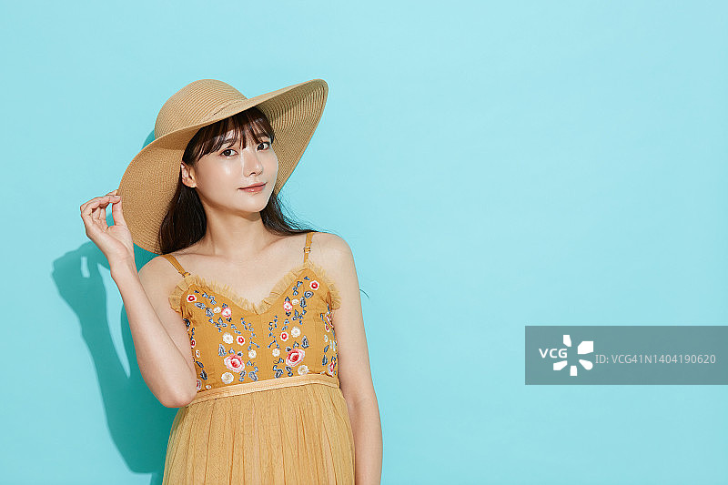年轻的亚洲女性肖像在度假时尚的蓝色背景图片素材