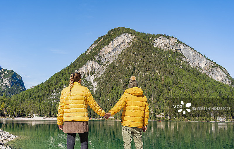 时尚夫妇牵着手，而步行附近高山湖泊图片素材