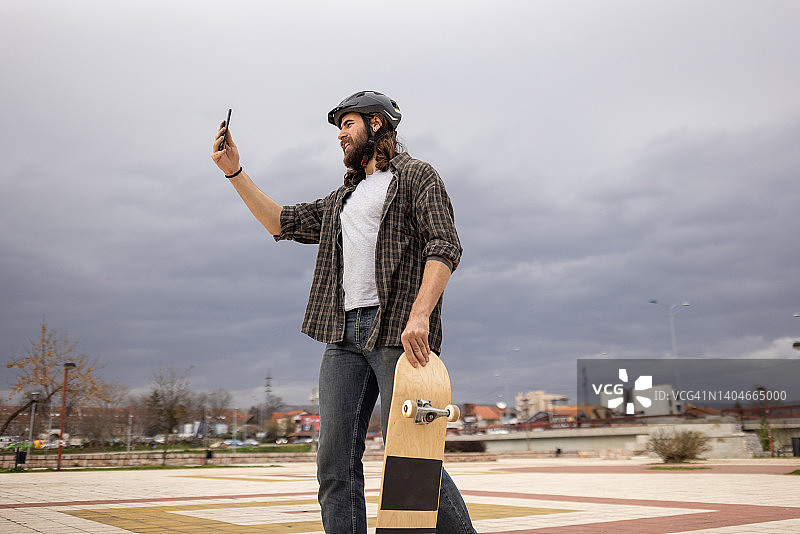 男性滑板者用手机自拍图片素材