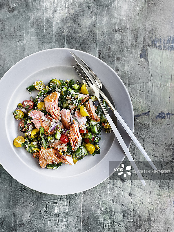 一盘烤鲑鱼配新鲜沙拉，灰色，风化的背景图片素材
