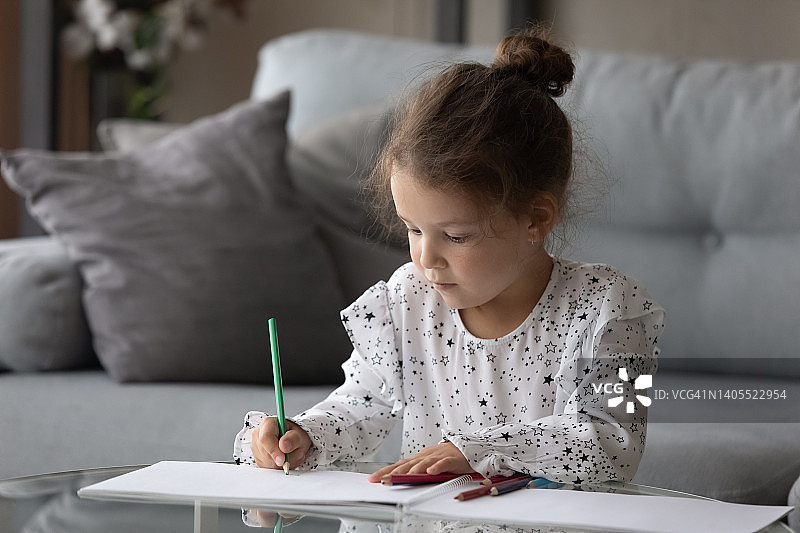 专注快乐可爱的小女孩在纸相册里画画。图片素材
