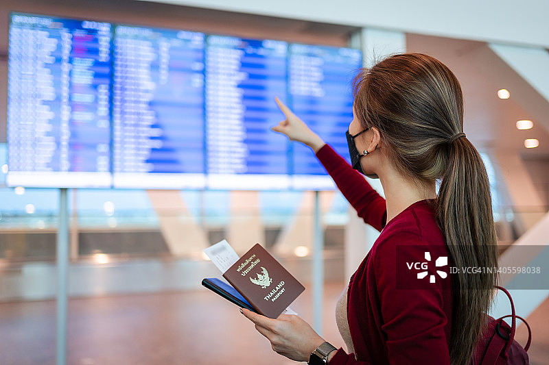 一位亚洲妇女在机场候机楼检查起飞时间图片素材